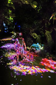 a woman walking down a pathway covered in colorful lights