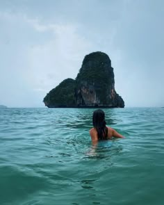 a woman swimming in the ocean with an island in the backgroung behind her