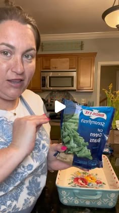 a woman holding up a bag of green beans