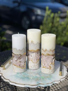 three white candles sitting on top of a metal tray next to a blue and black car