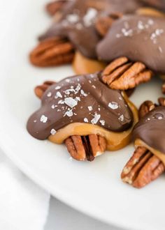 chocolate covered pretzels topped with pecans and caramels on a white plate