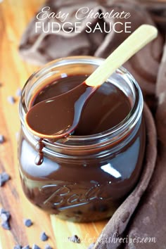 chocolate fudge sauce in a glass jar with a wooden spoon