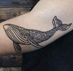 a black and white whale tattoo on the arm