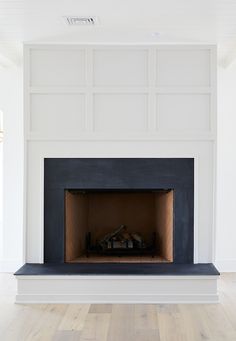 an empty living room with a fireplace and white walls