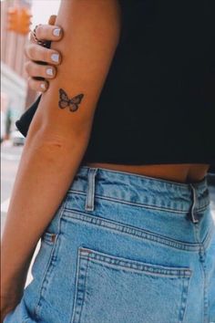 a woman with a small butterfly tattoo on her left arm and right hand behind her back