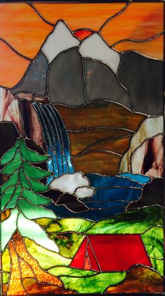 a stained glass window with mountains and trees