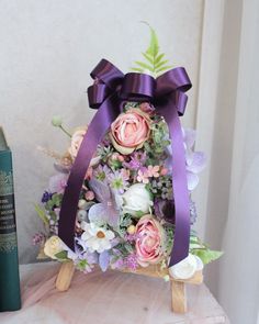 an arrangement of flowers and greenery is displayed on a table next to a book