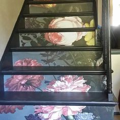 a stair case with flowers painted on the side and hand painted to match it's color scheme