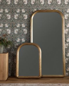 two mirrors sitting next to each other in front of a floral wallpapered wall