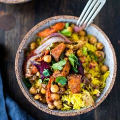 a bowl filled with rice, chickpeas and carrots next to a fork