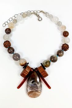 Silver & Stone Necklace - This necklace features a beautiful Coyamito agate peardrop pendant, embraced by vintage, sheer brandy-hued bakelite and molded wood bakelite. A polished study in chocolate tones and cream, it also features phantom agate, auralite 23, Victorian vulcanite beads, ghost quartz, and tourmaline quartz highlighted with Arizona turquoise. The necklace is 14 inches long with a sterling silver hinged hook clasp and a 4-inch sterling extender chain. Unique Carved Brown Necklace, Unique Brown Carved Necklace, Unique Brown Teardrop Necklace, Vintage Brown Agate Necklace, Brown Vintage Agate Necklace, Brown Carved Agate Jewelry, Coyamito Agate, Auralite 23, Artisan Jewelry Necklaces