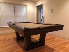 a pool table in an empty room with hard wood flooring and blinds on the windows