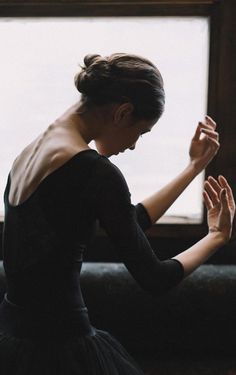 a woman in a black dress holding her hands together