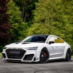 a white audi sports car parked in front of some trees and bushes on the side of the road