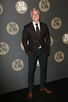 a man in a suit and tie standing on a black carpet with an oval logo behind him