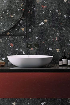 Black Galaxy Terrazzo Effect Tiles on a SplashBack in a Bathroom Behind a White Bowl Shaped Sink with Black Accents with a Deep Red Unit Dark Terrazzo, Black Terrazzo, Bathroom Styling