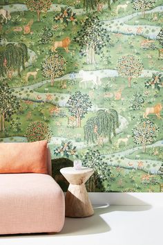 a pink chair sitting in front of a green wallpaper with deer and trees on it