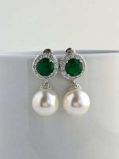 I've created this elegant green emerald cubic zirconia and pearl bridal jewelry set in rhodium plated brass setting and the set includes: # Earrings feature large 12mm Swarovski pearls that dangle from brilliant cut green emerald cubic zirconia with halo setting 12mm ear stud. Halo setting gives a brilliantly beautiful effect. Total length of the earrings is 2.8 cms. #Classic pearl bridal necklace and pendant set with rhodium plated brass peg and bail. Necklace features a pendant with large 12mm Green Round Pearl Drop Jewelry, Green Pearl Jewelry For May Birthstone, Elegant White Emerald Jewelry, Green Pearl Earrings For Wedding, Classic Green Pearl Drop Jewelry, Classic Green Earrings For Wedding, Green Pearl Drop Wedding Jewelry, White Emerald Jewelry For Wedding, Green Pearl Drop Jewelry For Wedding