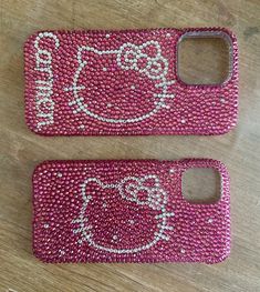 two cell phones with hello kitty on them sitting next to each other in front of a wooden table