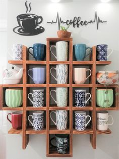 coffee cups and mugs are arranged on wooden shelves in front of a wall sign