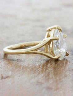 a yellow gold engagement ring with an oval cut diamond in the center on a wooden surface