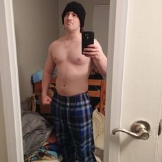 a shirtless man taking a selfie in his pajamas