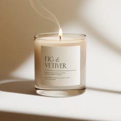 a candle with a white label on it sitting in front of a light colored background