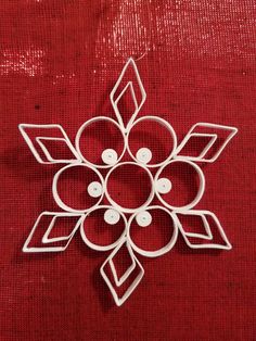 a snowflake made out of white paper on a red cloth with buttons in the center