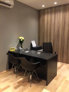 a desk with two chairs and a laptop on it in front of a wood paneled wall