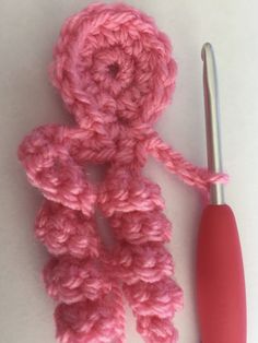 a crocheted pink object next to a knitting needle