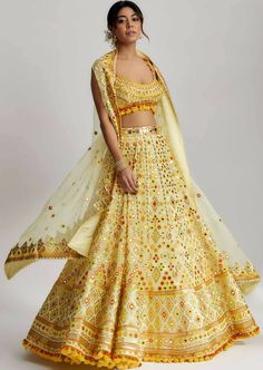 To further enhance its beauty, the ashi lehenga is adorned with pompoms and tassels. These playful elements add a whimsical touch and create a sense of movement as you glide across the dance floor. The pompoms and tassels are meticulously crafted and delicately attached, ensuring they stay in place throughout your glamorous wedding ceremony. Yellow Lehenga For Haldi, Lehenga With Cape, Organza Cape, Beautiful Gown Designs, Gopi Vaid, Haldi Dress, Brocade Lehenga, Cape Set, Indian Outfits Lehenga