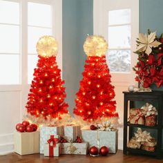 two red christmas trees with lights and presents in front of them on a wooden floor