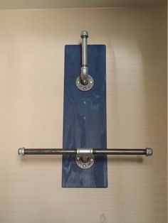 two metal pipes are attached to the wall above a toilet paper dispenser