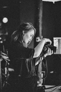 a black and white photo of a woman holding a camera