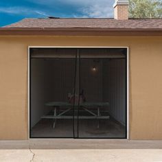 an empty picnic table sits in front of a garage door that opens to the outside