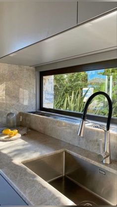 a kitchen with a sink, counter top and window looking out onto the outside area