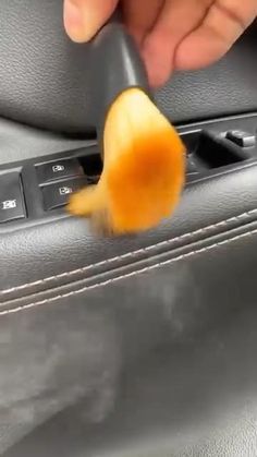 a person is peeling an orange peel in the center console of a car with their hand