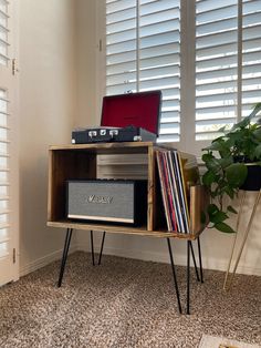 a record player sitting on top of a wooden shelf next to a window with shutters