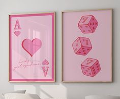 two pink framed pictures with hearts and dices on them in a white room next to a bed