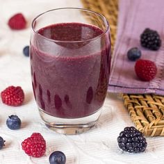 berry burst juice in a glass next to berries and raspberries on a table