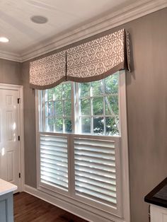 an empty kitchen with white cabinets and window coverings on the windowsill in front of the sink