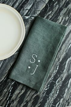 a plate and napkin on a marble table with the word sj printed on it