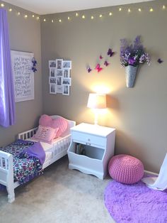 a bedroom decorated in purple and white with flowers on the wall, bedding and rugs