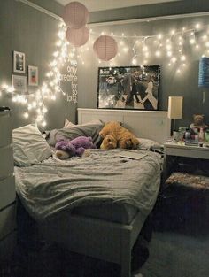 a bedroom with lights strung from the ceiling and stuffed animals on the bed in front of it