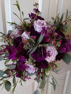 a bouquet of purple flowers is hanging on the front door