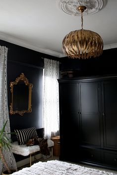 a bedroom with black walls, white curtains and a gold chandelier hanging from the ceiling