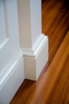 the corner of a room with wood flooring and white trim