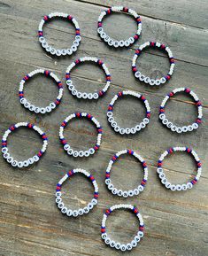 six bracelets made out of plastic beads on top of a wooden table next to scissors