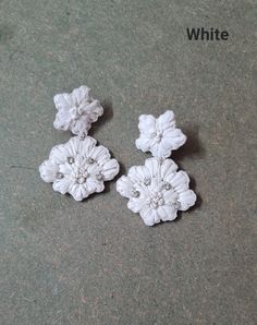 three white flowers are sitting on the ground