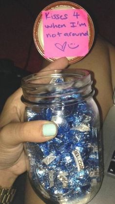 a person holding a jar filled with blue candies in front of a laptop computer